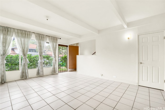 tiled empty room featuring beam ceiling