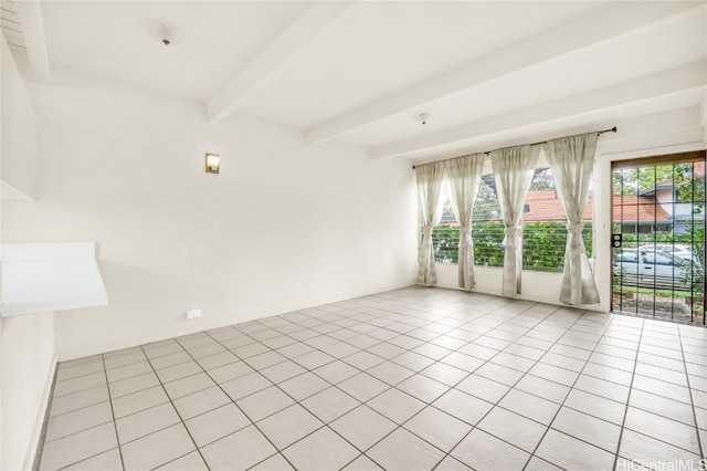 empty room featuring beamed ceiling and light tile patterned floors