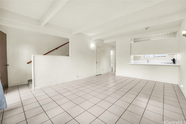 unfurnished living room with beam ceiling and light tile patterned floors