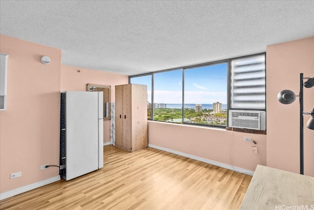 spare room with cooling unit, baseboards, a textured ceiling, and wood finished floors