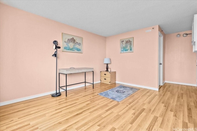 interior space with light wood-style flooring, baseboards, and a textured ceiling
