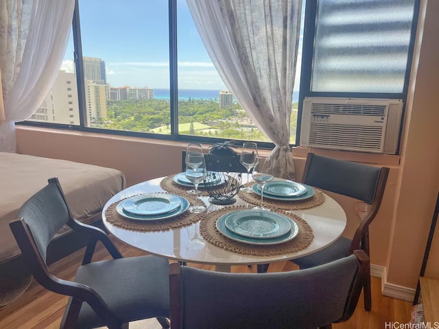 dining room featuring cooling unit, a view of city, and wood finished floors
