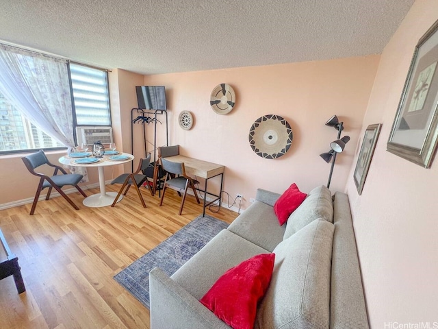 living area with baseboards, cooling unit, wood finished floors, and a textured ceiling