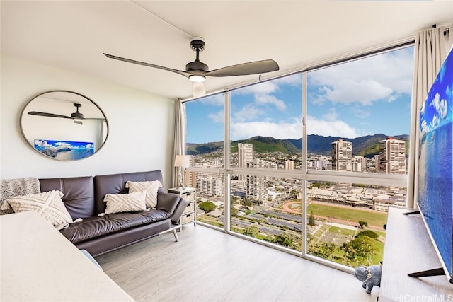 sunroom / solarium with a city view, a ceiling fan, and a mountain view