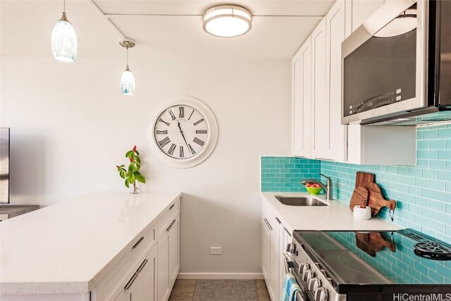 kitchen featuring decorative backsplash, stainless steel appliances, sink, pendant lighting, and white cabinets