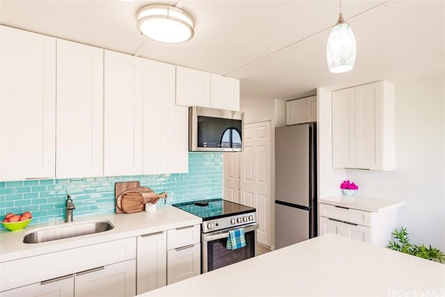 kitchen featuring white cabinetry, sink, backsplash, pendant lighting, and appliances with stainless steel finishes