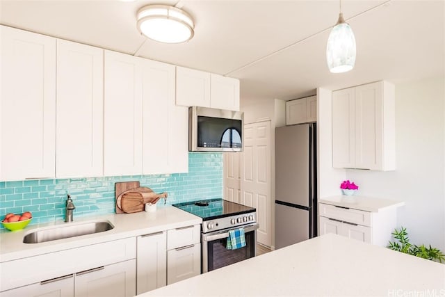 kitchen with backsplash, light countertops, appliances with stainless steel finishes, white cabinets, and a sink