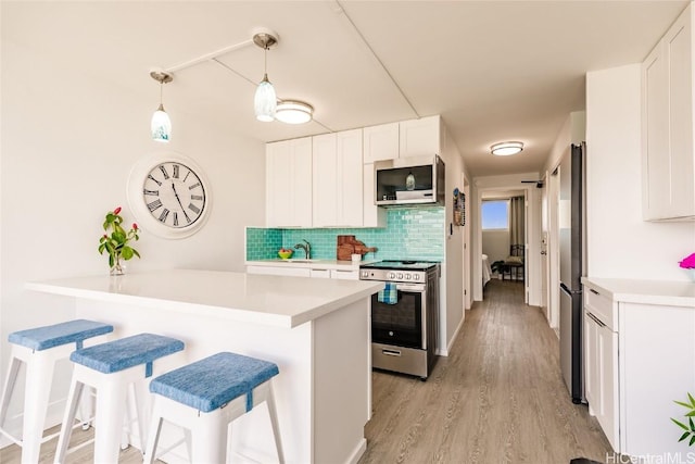 kitchen featuring decorative backsplash, a breakfast bar area, white cabinets, and appliances with stainless steel finishes