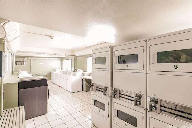 shared laundry area with light tile patterned floors, separate washer and dryer, a textured ceiling, and stacked washer and dryer