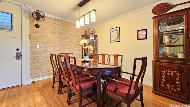 dining space featuring ornamental molding and light hardwood / wood-style flooring