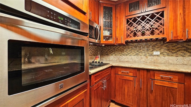 kitchen with light stone counters, stainless steel appliances, and backsplash