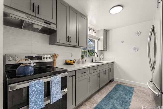 kitchen featuring sink, appliances with stainless steel finishes, decorative backsplash, and gray cabinetry