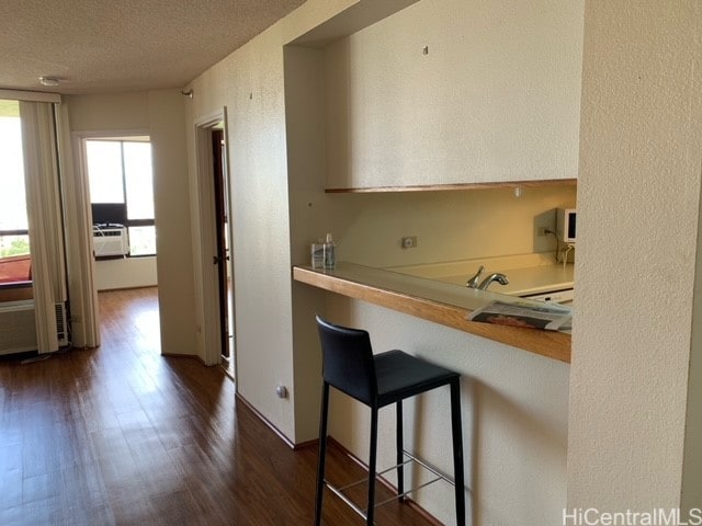 kitchen with a kitchen breakfast bar, dark hardwood / wood-style floors, and a textured ceiling