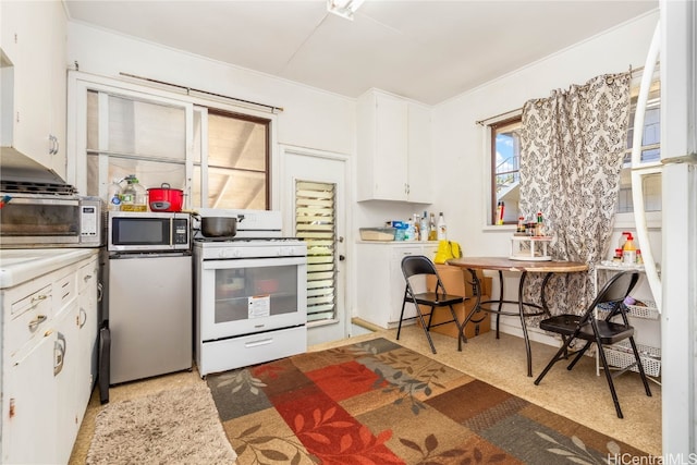 kitchen featuring white cabinetry, white gas range oven, and light colored carpet