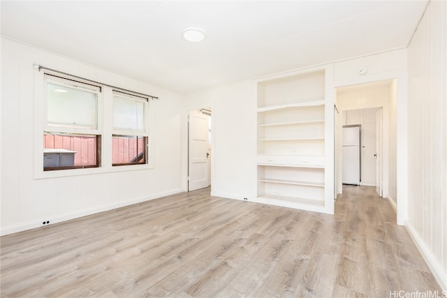 unfurnished bedroom with light hardwood / wood-style floors and white refrigerator