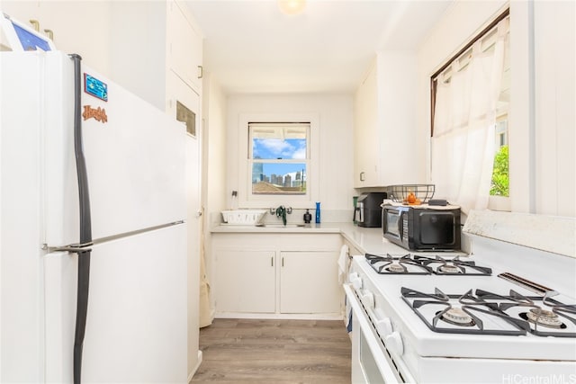 kitchen with white appliances, white cabinetry, sink, and light wood-type flooring