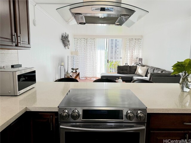 kitchen with stainless steel appliances, open floor plan, light countertops, and dark brown cabinetry