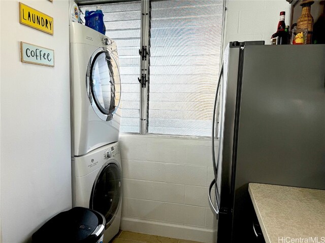 laundry room featuring stacked washer and dryer, laundry area, and concrete block wall