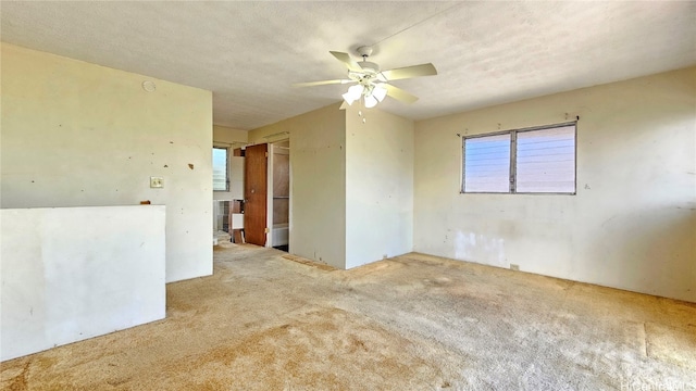 empty room featuring a textured ceiling, light colored carpet, and ceiling fan