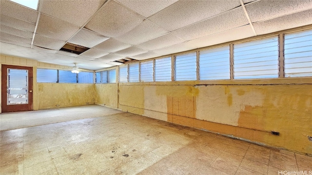 basement featuring a drop ceiling, a wealth of natural light, and ceiling fan