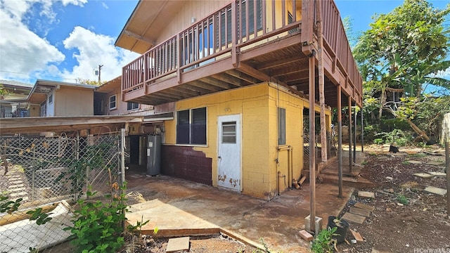 back of house featuring a wooden deck, concrete block siding, electric water heater, and fence