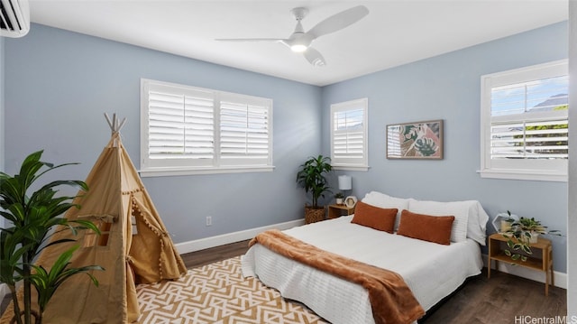 bedroom with ceiling fan, a wall mounted AC, and dark hardwood / wood-style floors