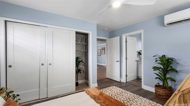 bedroom with an AC wall unit, ensuite bath, dark hardwood / wood-style flooring, and ceiling fan