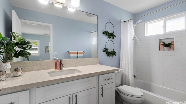 full bathroom featuring vanity, shower / tub combo with curtain, toilet, and a wealth of natural light