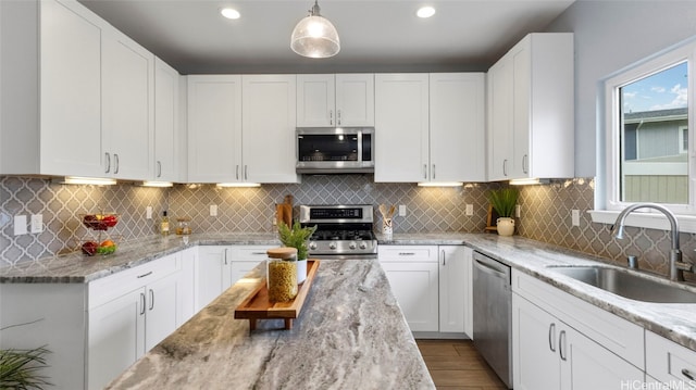 kitchen with backsplash, stainless steel appliances, pendant lighting, and white cabinets