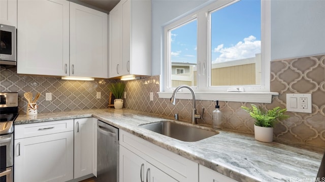 kitchen with white cabinetry, sink, backsplash, and stainless steel appliances