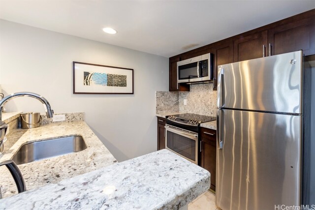 kitchen featuring light stone countertops, appliances with stainless steel finishes, sink, and backsplash