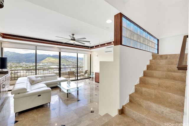 tiled living room with a wall mounted AC, a tray ceiling, plenty of natural light, and ceiling fan