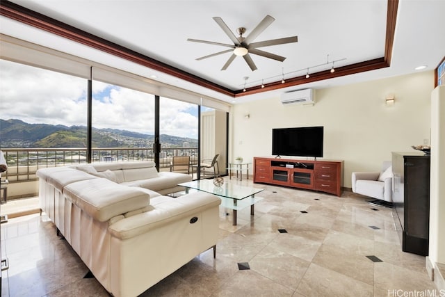 living room featuring a wall unit AC, a mountain view, a tray ceiling, crown molding, and ceiling fan