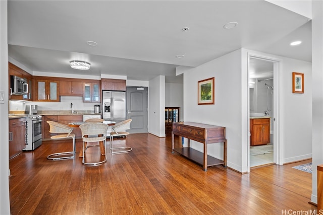 kitchen with stainless steel appliances, sink, a kitchen breakfast bar, and hardwood / wood-style floors