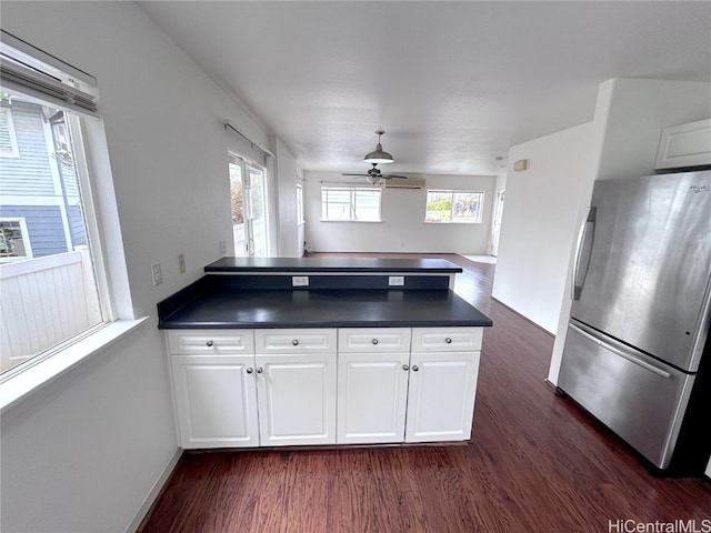 kitchen featuring stainless steel refrigerator, kitchen peninsula, white cabinets, and dark hardwood / wood-style flooring