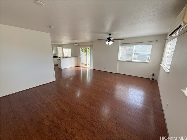 unfurnished living room with dark hardwood / wood-style floors, a healthy amount of sunlight, a textured ceiling, and ceiling fan