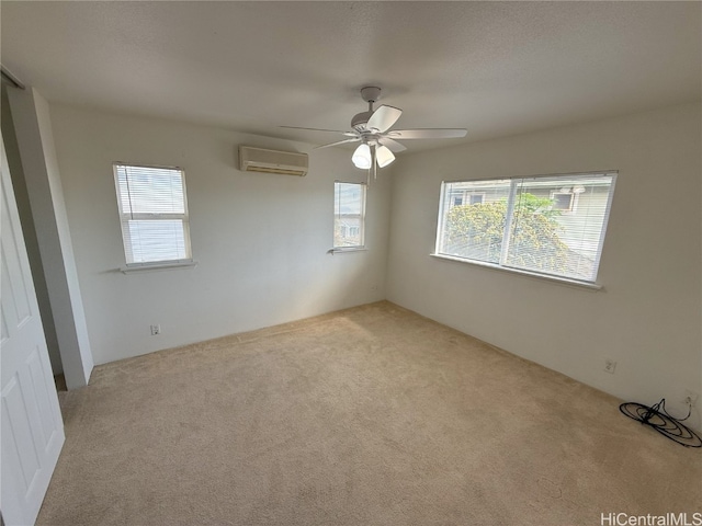 spare room with ceiling fan, light colored carpet, and a wall unit AC