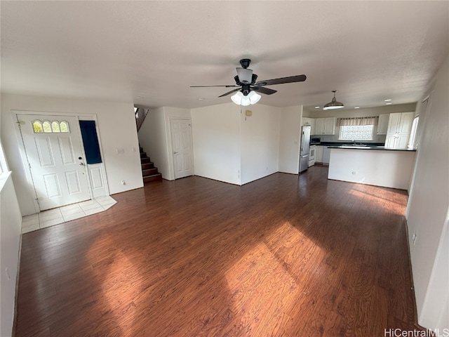 unfurnished living room featuring dark hardwood / wood-style floors, ceiling fan, and sink