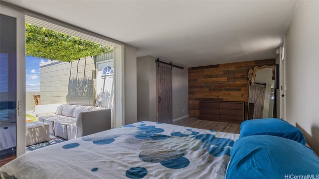 bedroom featuring wood walls, a barn door, and hardwood / wood-style floors