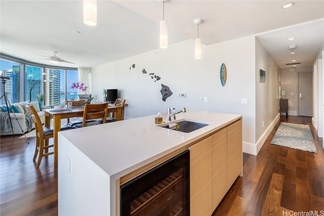 kitchen featuring sink, an island with sink, hanging light fixtures, beverage cooler, and dark hardwood / wood-style floors