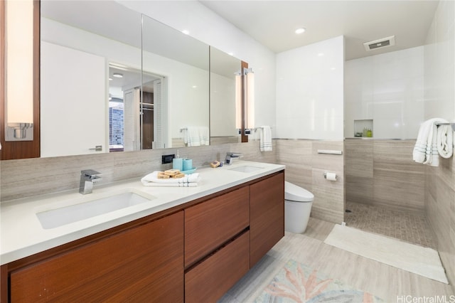 bathroom featuring tile walls, vanity, toilet, and walk in shower