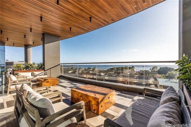 balcony featuring an outdoor living space with a fire pit and a water view