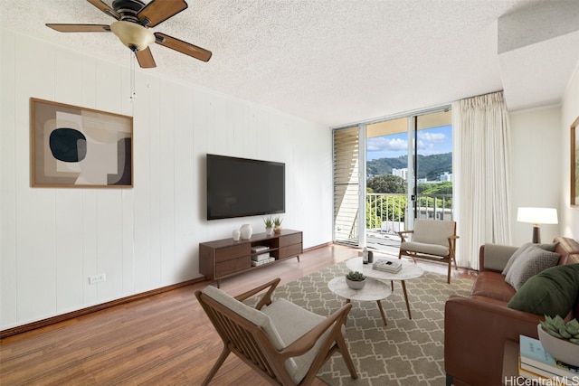 living room with ceiling fan, wood-type flooring, and a textured ceiling