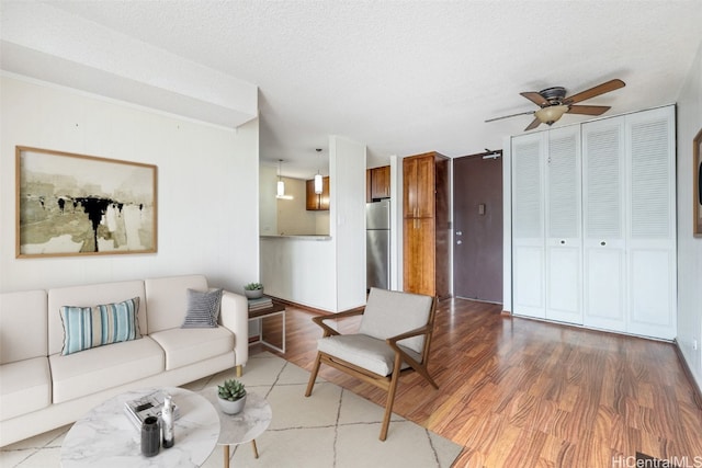 living room with hardwood / wood-style floors, a textured ceiling, and ceiling fan