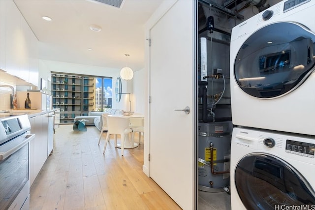 clothes washing area with light hardwood / wood-style floors and stacked washer and clothes dryer