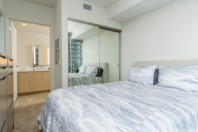 bedroom featuring light carpet, a closet, sink, and connected bathroom