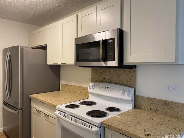 kitchen with a textured ceiling, light stone counters, white cabinetry, and stainless steel appliances