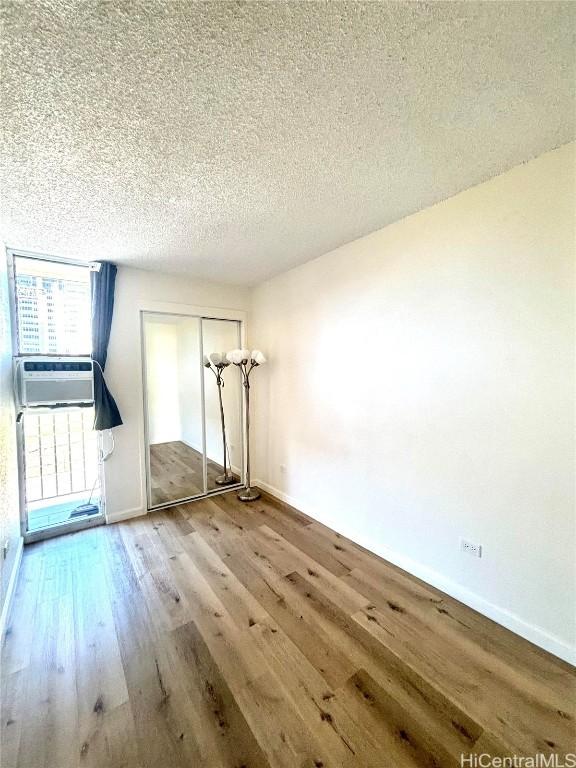 unfurnished room featuring a textured ceiling, hardwood / wood-style flooring, and cooling unit