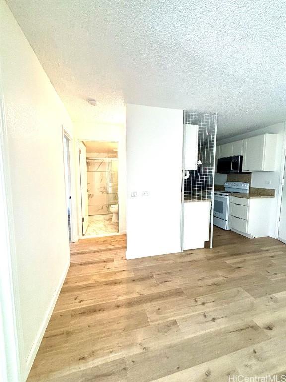 kitchen with white cabinets, a textured ceiling, light hardwood / wood-style flooring, and white electric stove