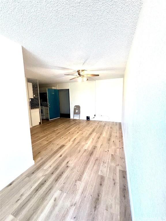 unfurnished living room with ceiling fan, light hardwood / wood-style floors, and a textured ceiling